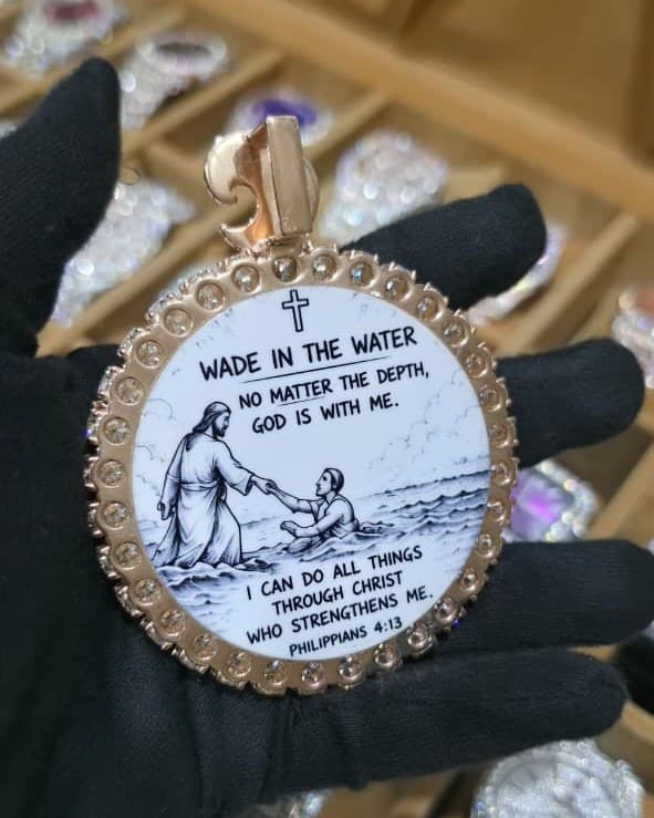 Round rose gold medallion with printed artwork under glass and a bezel set with stones, held in a black glove